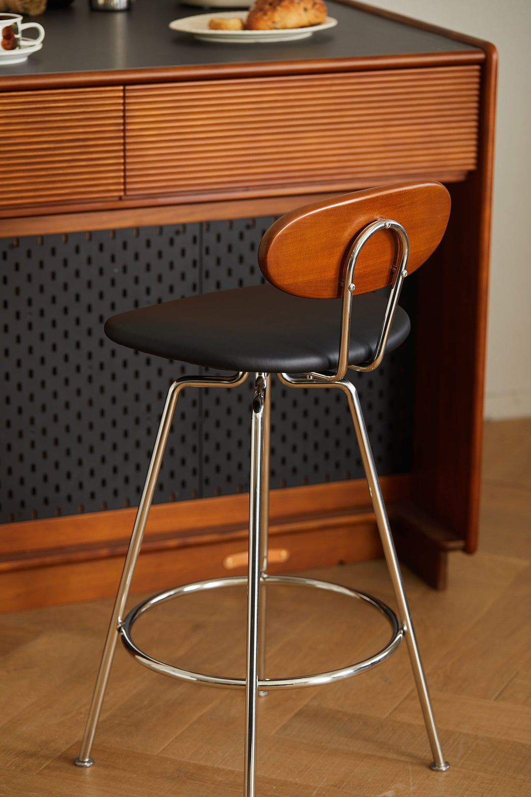 Bar chair with black seat and chrome legs in front of a wooden desk. Loft Home bar chairs collection cover picture.