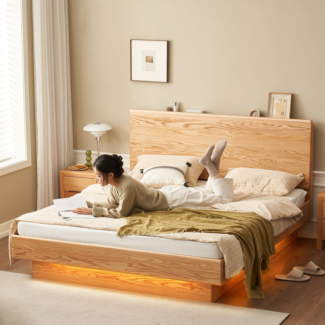 Loft Home new arrival bed frame with a natural wood grain finish and ambient LED under-bed lighting, styled with soft beige bedding and a cozy reading setup, enhancing tranquil bedroom aesthetics.