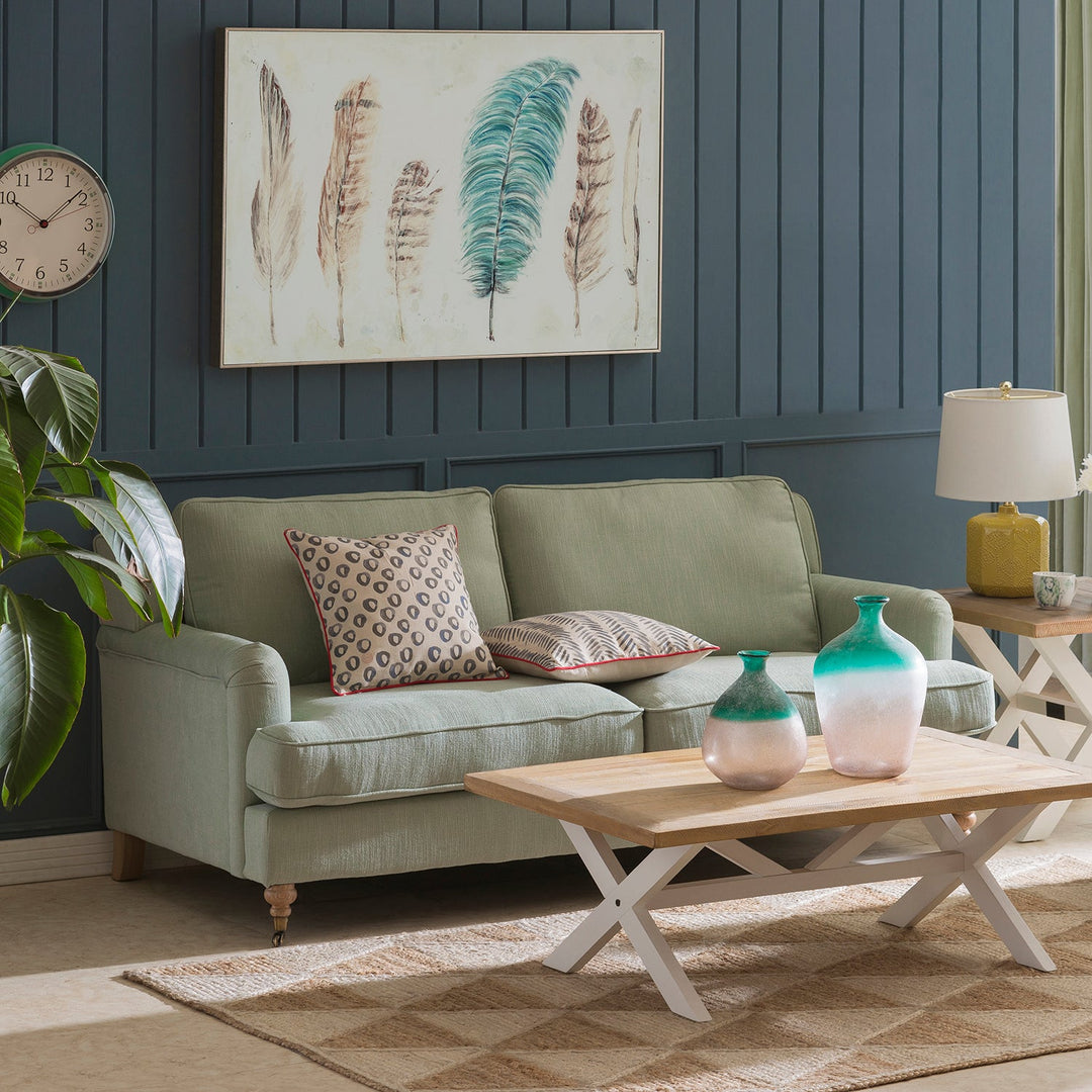 Loft Home new arrival green fabric sofa, styled with patterned cushions and rustic wood coffee table, perfect for cozy and stylish living room aesthetics.