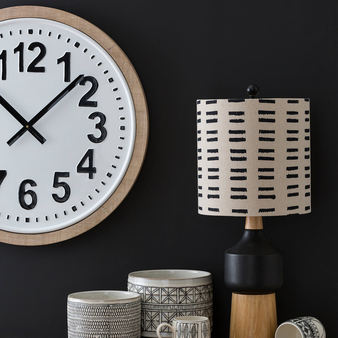 Modern wall clock with bold numbers paired with a geometric-patterned table lamp, accompanied by decorative ceramic jars, creating a stylish and contemporary decor arrangement.