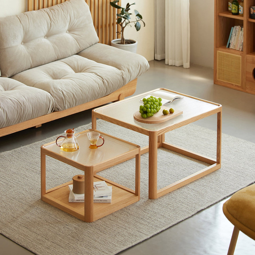 Minimalist stackable coffee tables in natural wood finish, featuring a ribbed glass tabletop and compact design, ideal for versatile living spaces.