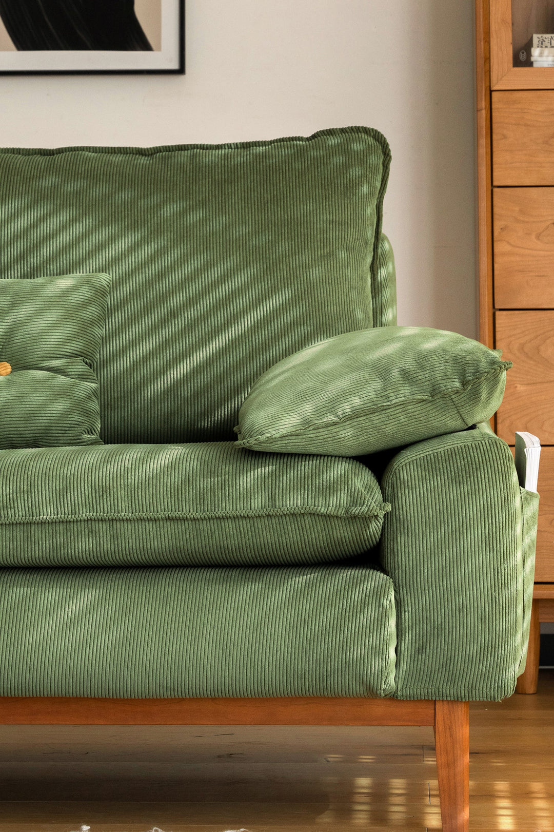 Green corduroy fabric sofa with wooden legs in a living room. Loft Home fabric sofa featured product.