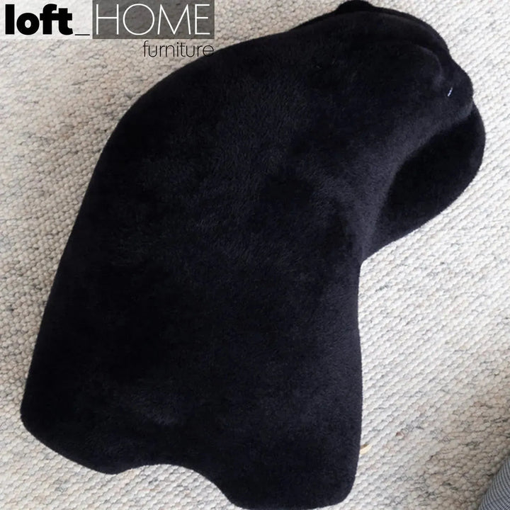 Contemporary velvet ottoman resting bear black material variants.