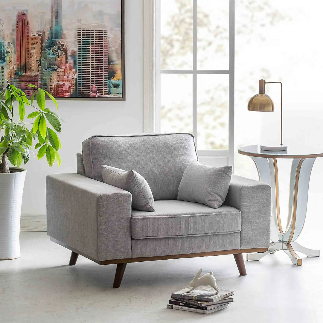 Modern living room with a stylish grey 1-seater sofa, complemented by contemporary decor and natural light from large windows, featured in Loft Home's 1-seater sofa collection.