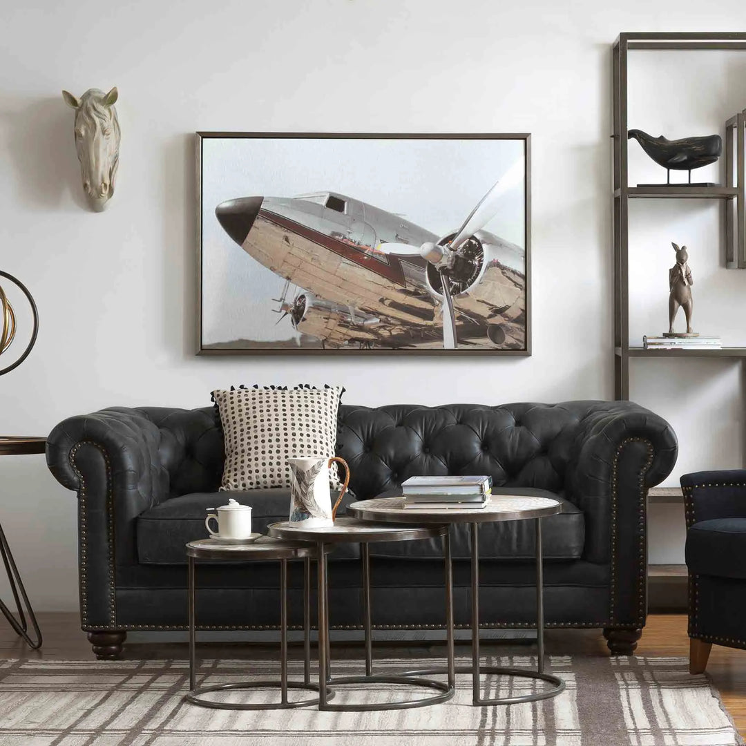 Elegant living room with a black leather 2-seater sofa, stylish coffee tables, and aviation-themed wall art, featured in Loft Home's 2-seater sofa collection.