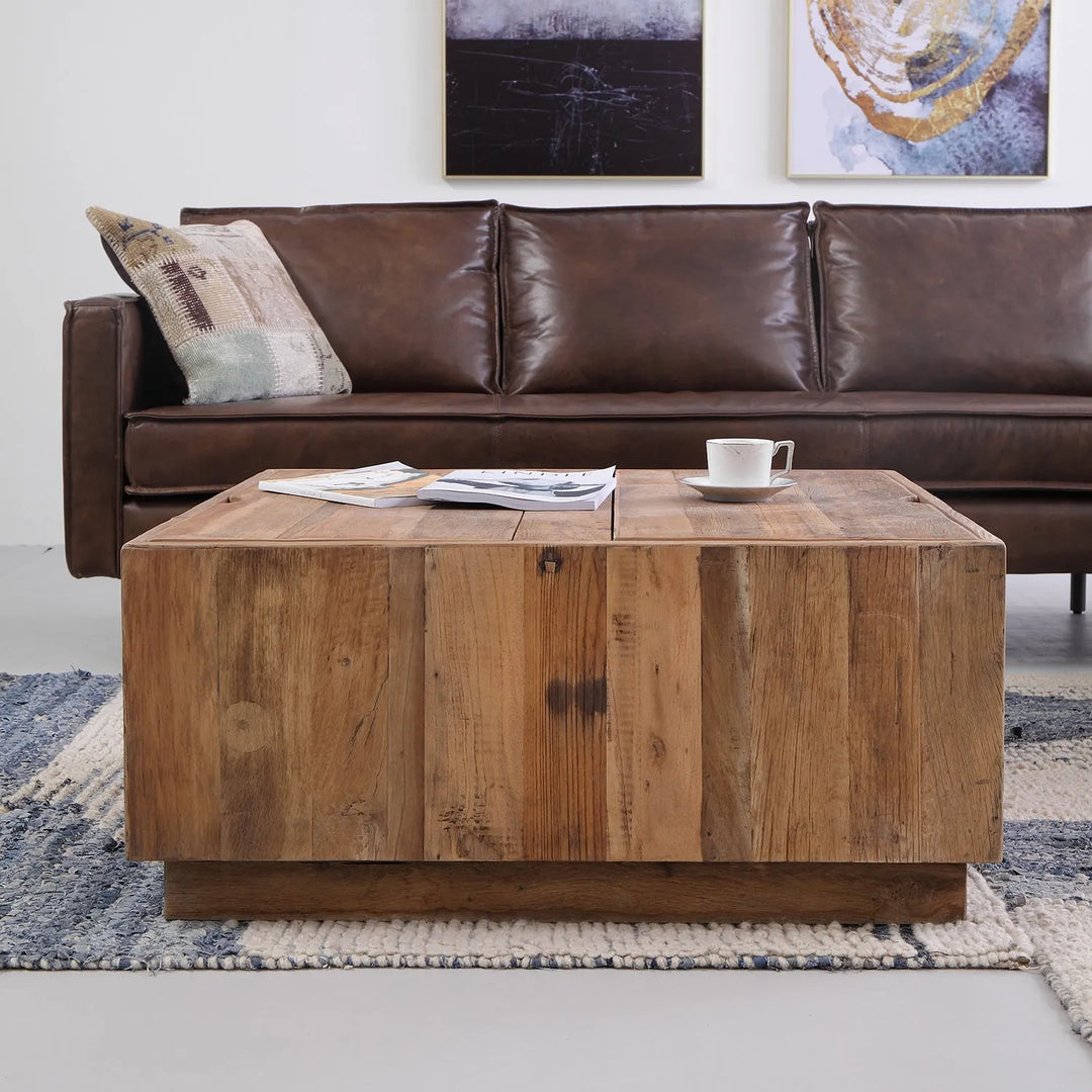 Bohemian living room setup featuring a rustic wooden coffee table, a brown leather sofa, and eclectic wall art, creating a warm and inviting space with a cozy and relaxed vibe.