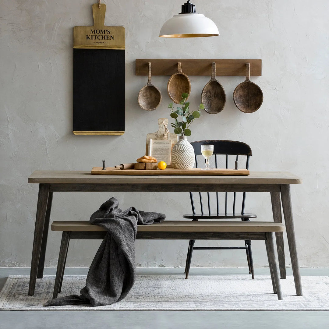 Rustic dining area with a wooden table and matching bench, decorated with vintage kitchenware and a cozy ambiance, ideal for a farmhouse-inspired interior.