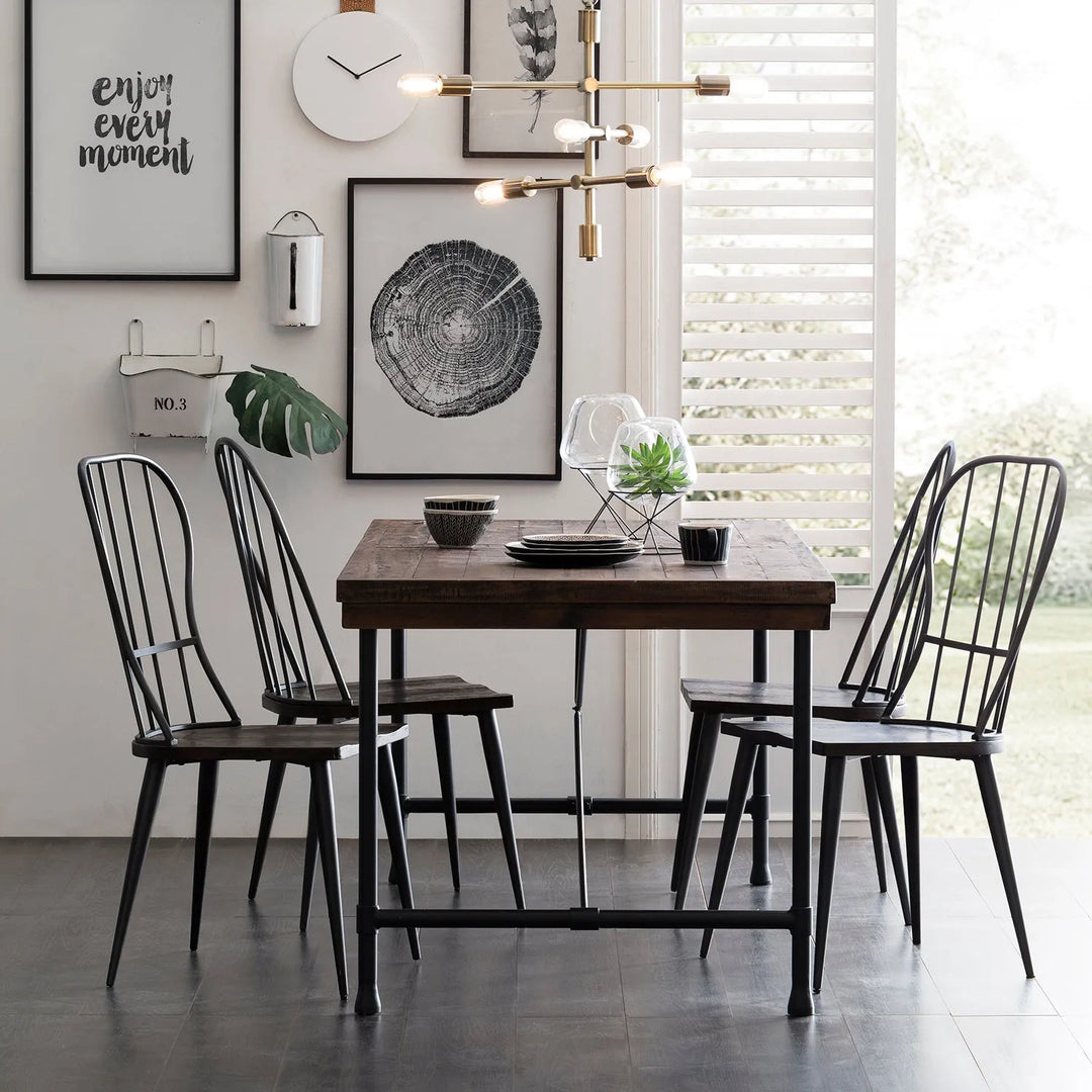 Industrial dining room setup featuring a wooden table with metal legs, black metal chairs, and modern wall art, creating a chic and contemporary look ideal for urban home interiors.