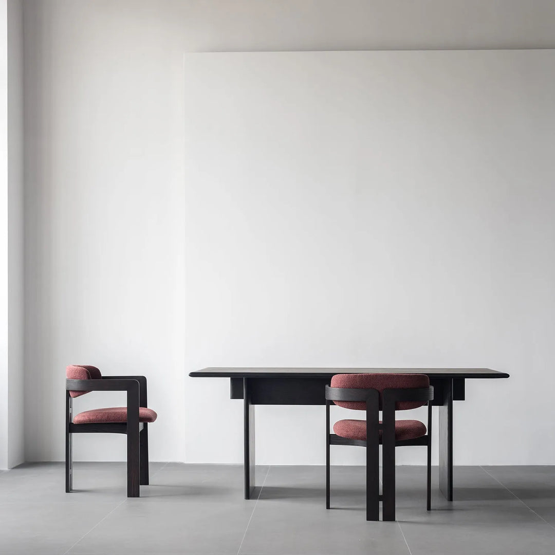 Japandi style dining setup featuring a sleek black table and two modern chairs with red cushioned seats, embodying a blend of Japanese minimalism and Scandinavian functionality.