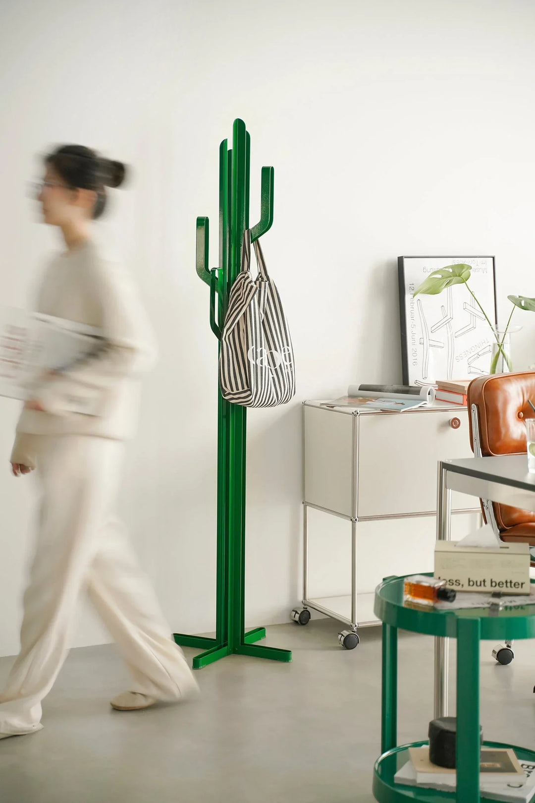 Green cactus-shaped clothes hanger with a striped bag against a white wall. Loft Home clothes hangers collection cover photo.