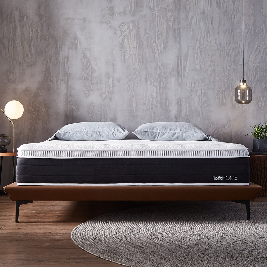 Modern bedroom with a stylish mattress on a sleek bed frame, featuring soft pillows, a round rug, and minimalist lighting for a cozy ambiance.