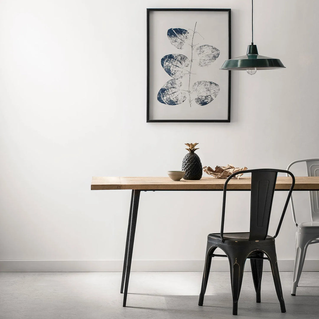 Modern dining room setup featuring a wooden table with metal legs, stylish metal chairs, a decorative pineapple, and minimalist wall art - perfect for contemporary home interiors.