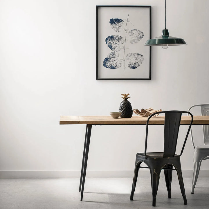 Modern dining room setup featuring a wooden table with metal legs, stylish metal chairs, a decorative pineapple, and minimalist wall art - perfect for contemporary home interiors.