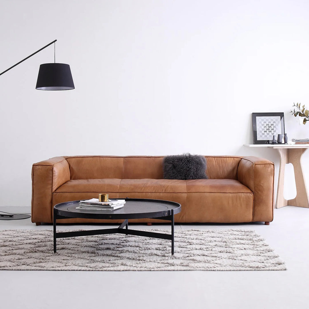 Modern living room with a sleek brown leather sofa, a stylish black coffee table, and minimalist decor, linking to Loft Home's regular sofa collection.