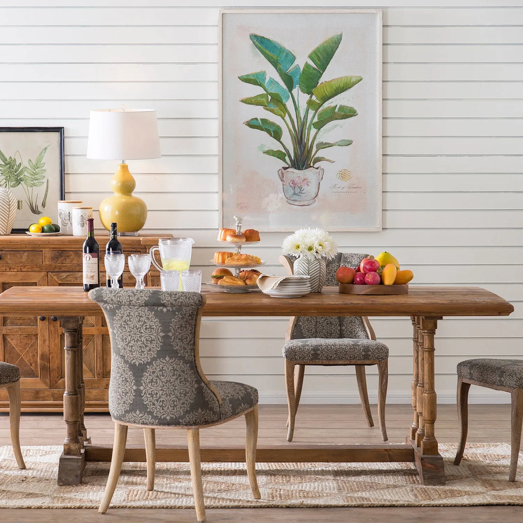 Elegant dining room with a wooden table featuring ornate legs, upholstered chairs with intricate patterns, and charming decor including a large botanical artwork and a variety of dining accessories, perfect for showcasing different table styles.