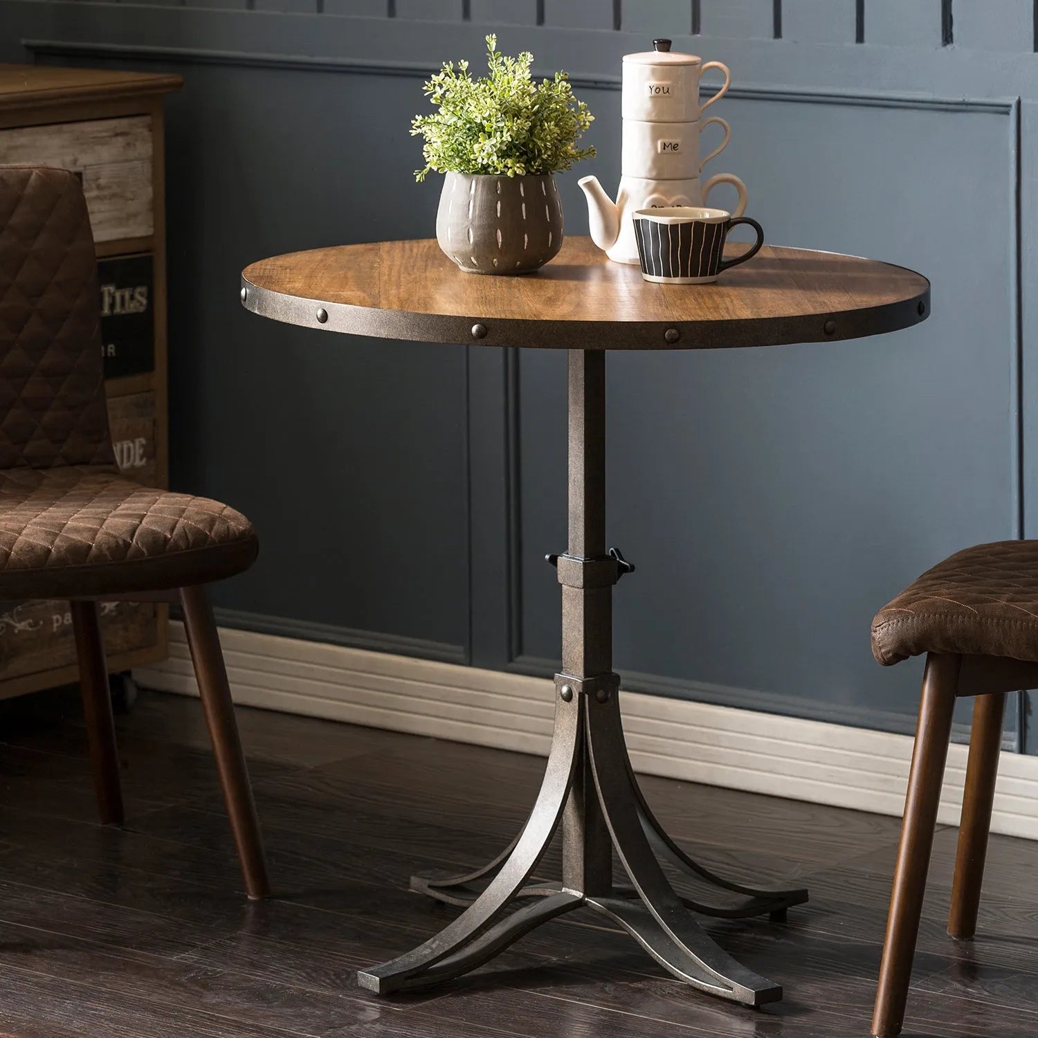 Industrial-style round table with a wooden top and metal base, accompanied by a stylish chair and rustic decor, perfect for a modern and robust home interior.