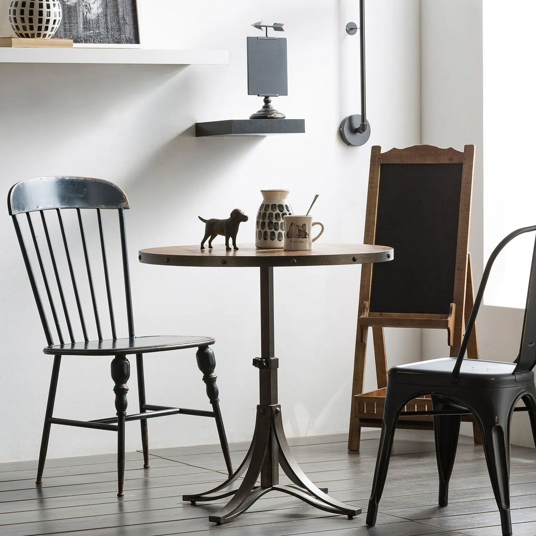 Eclectic dining nook with a round table featuring a wooden top and metal base, paired with vintage chairs and charming decor, ideal for a unique and stylish home interior.