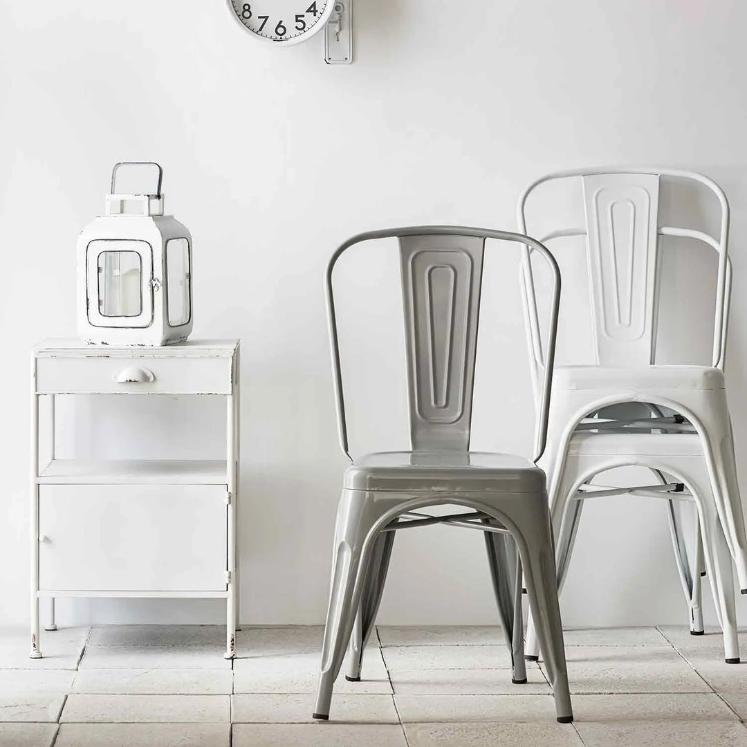 Featured in Loft Home's chairs collection: Minimalist setup with metal dining chairs, a rustic side table, and a vintage wall clock.