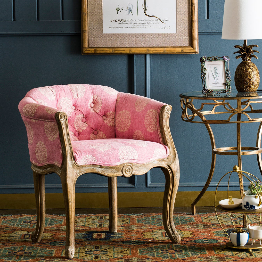 Elegant pink tufted armchair with a vintage wood frame, paired with a decorative side table, adding charm and sophistication to any space.