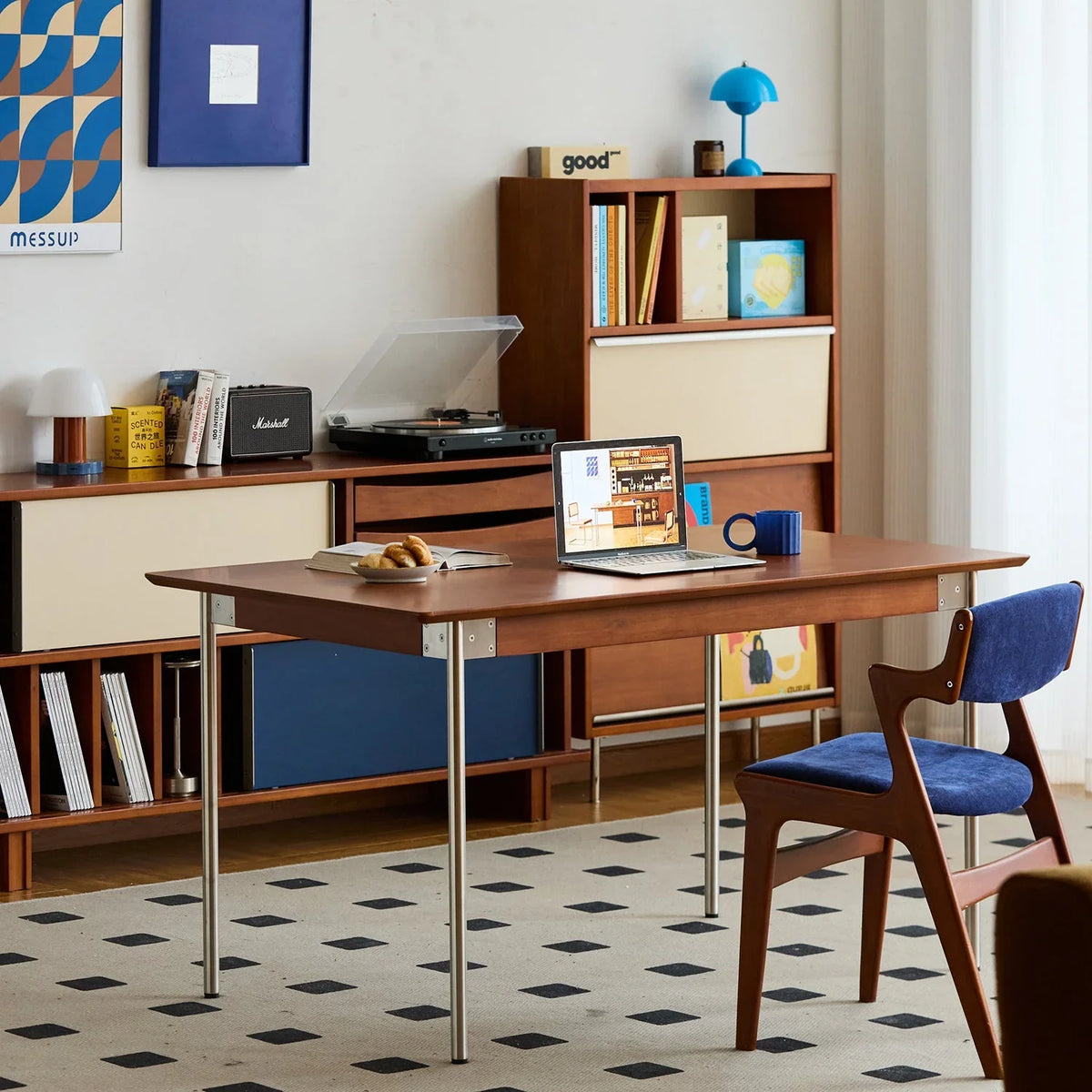 Bauhaus Style dining room and home office with wooden desk, laptop, and bookshelf.