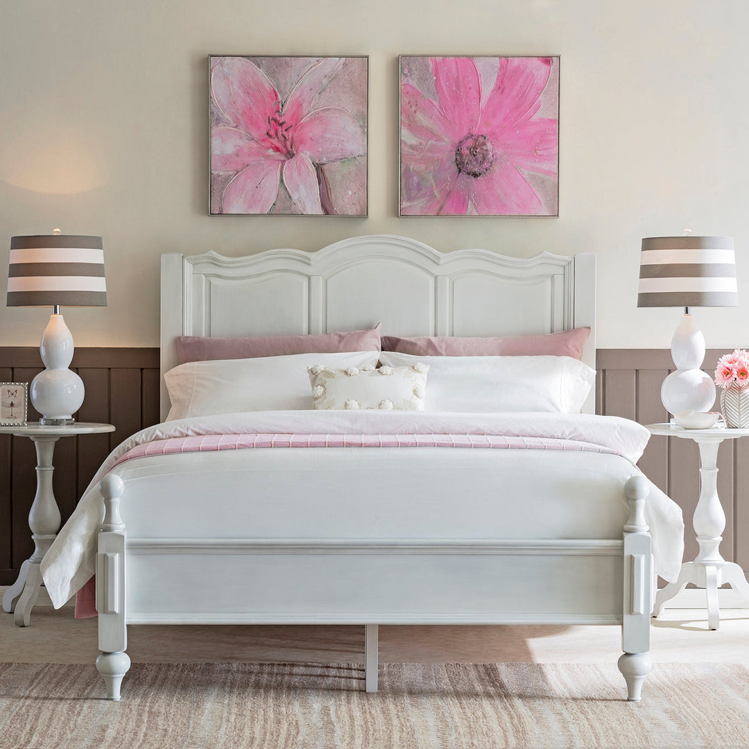 Loft Home elegant white wooden bed frame, styled with soft pink bedding and floral wall art, creating a serene and romantic bedroom ambiance.