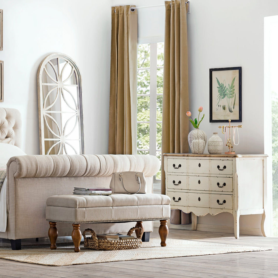 Loft Home bedroom storage setup featuring a vintage white dresser with elegant black handles, styled with decorative vases and a neutral upholstered bench, creating a serene and functional sleeping space.