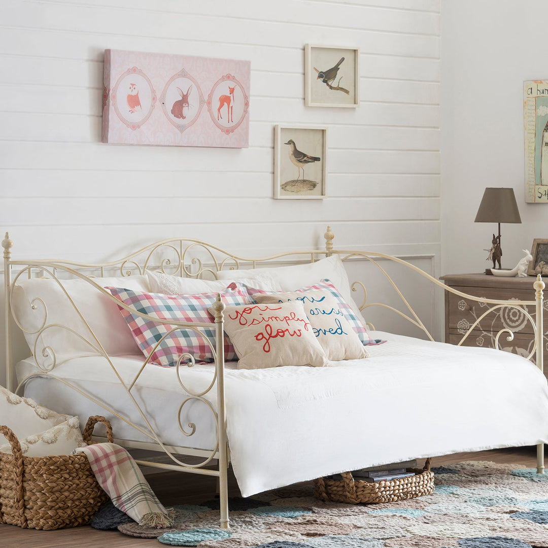 Loft Home vintage-style cream metal bed frame adorned with cozy plaid and embroidered cushions, offering a charming and budget-friendly bedroom centerpiece.