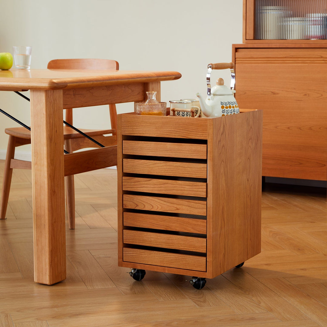 Cherry wood chest of drawers with wheels, featuring a slatted design for ventilation and mobility, ideal for versatile storage in dining or living spaces.