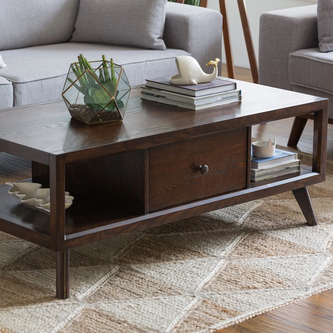 Industrial-style wooden coffee table with metal frame and storage drawers, placed in a cozy living space with a black leather sofa and rustic decor.