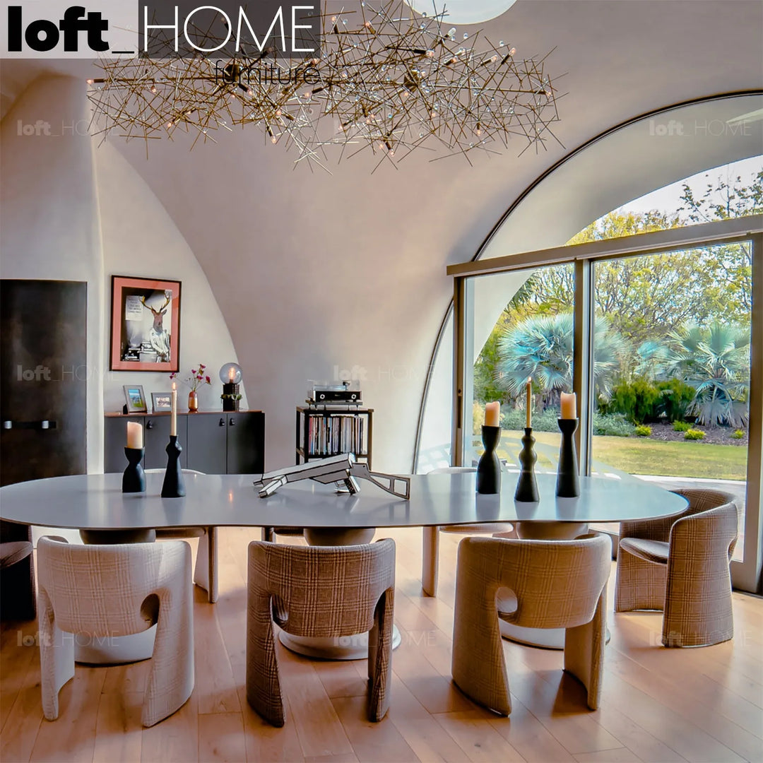 Loft Home modern dining room featuring a large oval table, contemporary chairs, and a statement chandelier, with floor-to-ceiling windows offering garden views.