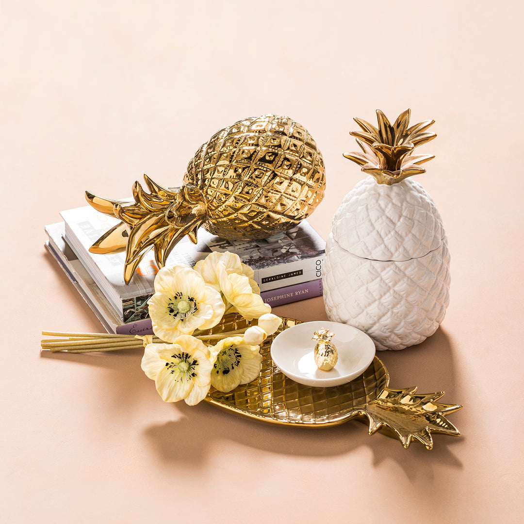 Loft Home decorative accents featuring gold and white pineapple ornaments, a floral arrangement, and a stylish tray for a modern and elegant display.