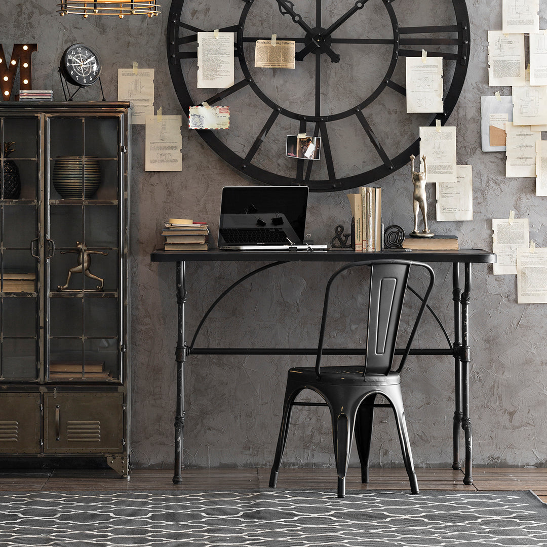 Loft Home industrial-style workspace featuring a black metal desk and chair, large wall clock, and vintage decor for a modern, minimalist office setting.