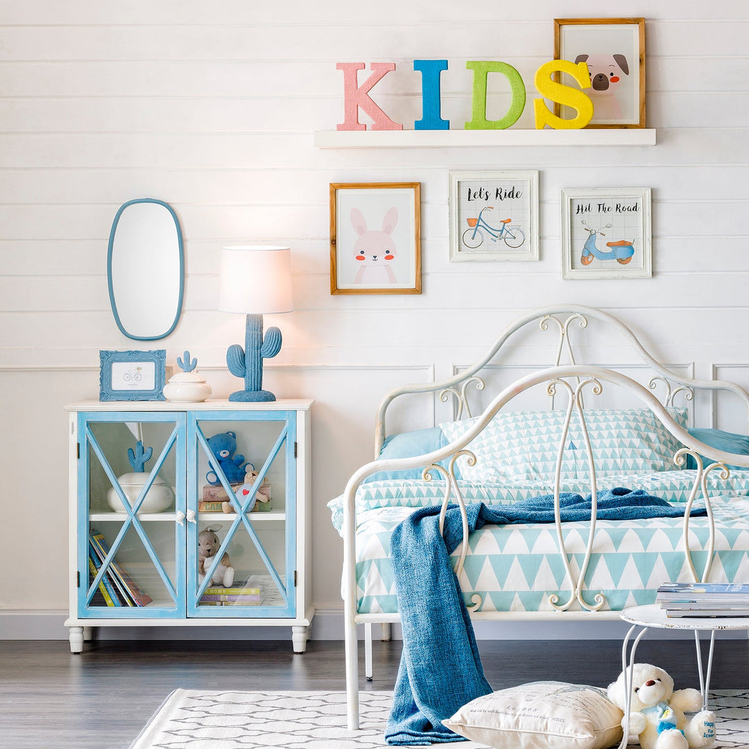 Children’s room with a metal bed frame, blue cabinet, playful wall decor, soft bedding, and toys, creating a cozy and fun space for kids.