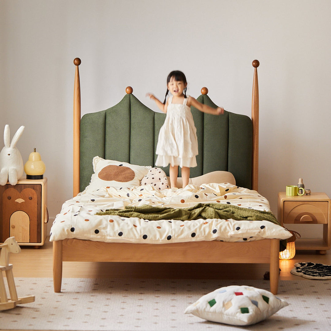 Child standing on a bed with a green headboard in a bedroom setting
