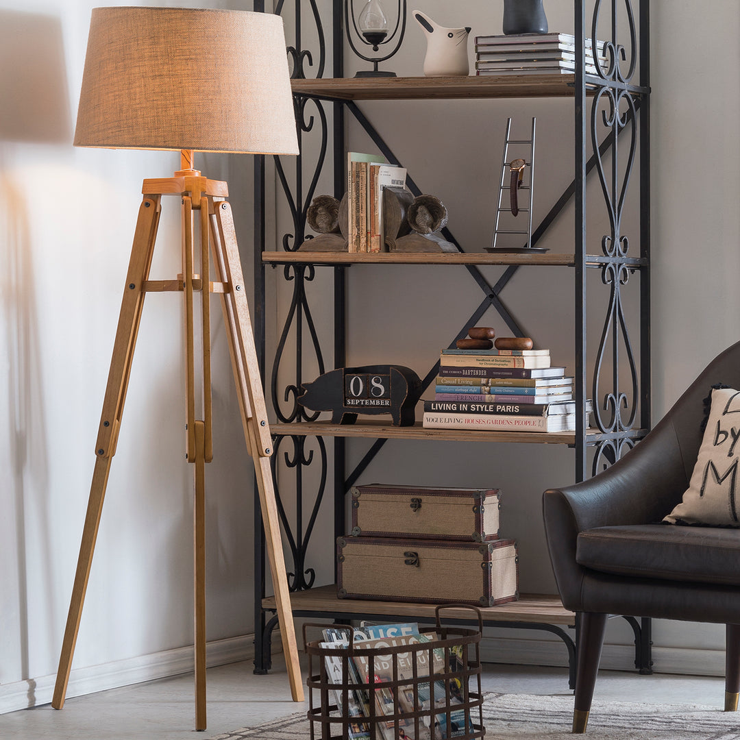 Loft Home cozy reading nook featuring a wooden tripod floor lamp, metal bookshelf with rustic decor, and a comfortable leather armchair