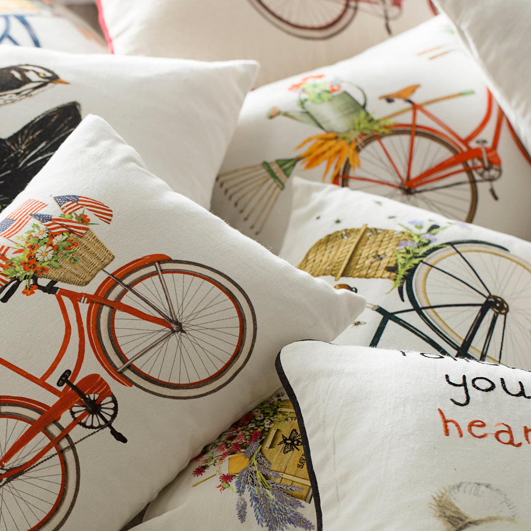 Decorative throw pillows featuring bicycle designs with baskets of flowers, adding a vintage and playful touch to any room decor.