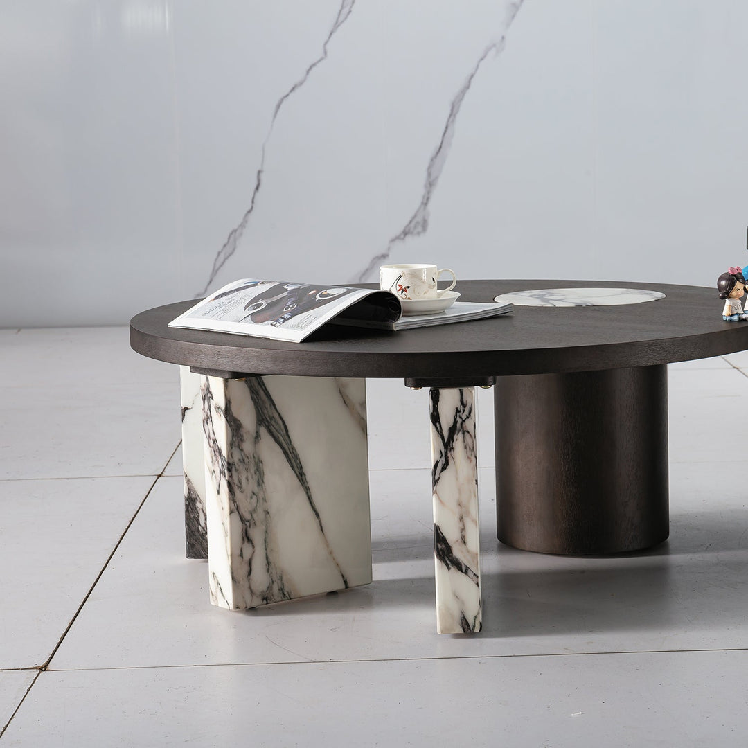 Round marble coffee table with sleek dark wood accents, featuring a luxurious design and sturdy marble legs for elegant living spaces.