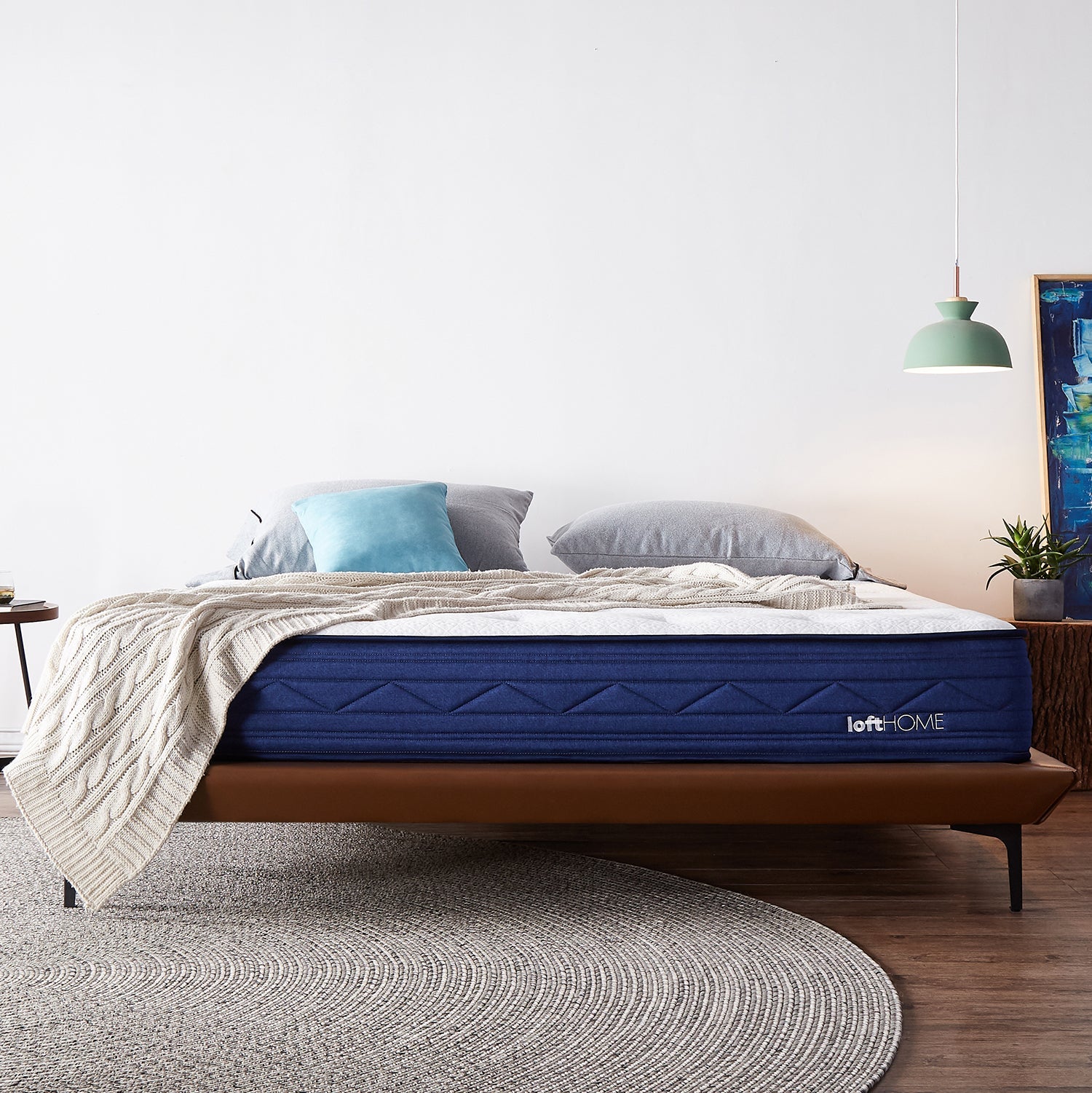 LoftHome premium mattress with blue fabric cover, paired with a minimalist bed frame, styled with cozy blankets and pillows, enhancing bedroom comfort and style.