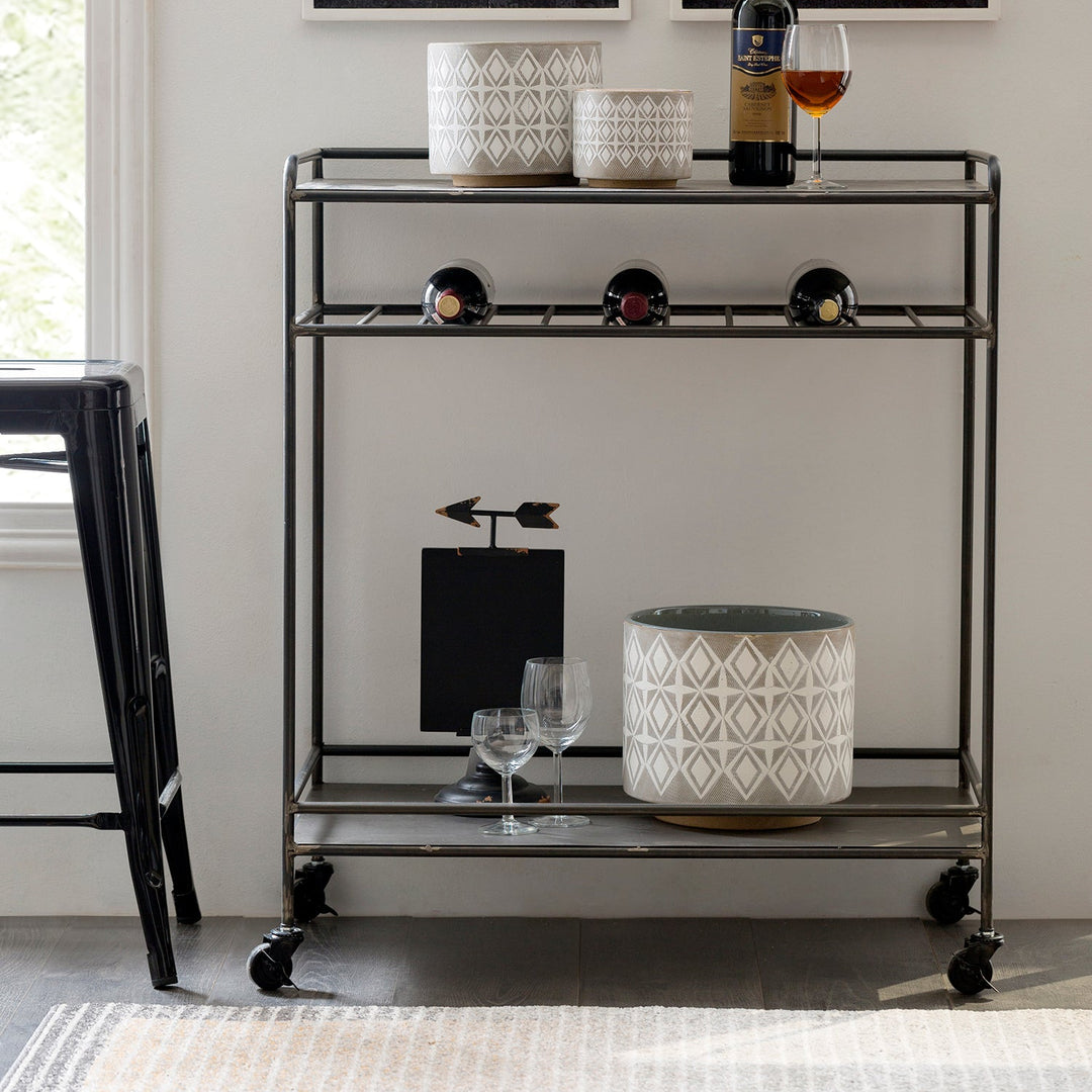 Loft Home metal storage rack with sleek black finish, featuring geometric ceramic planters, wine bottle holders, and glassware, offering a modern and practical solution for versatile home storage.