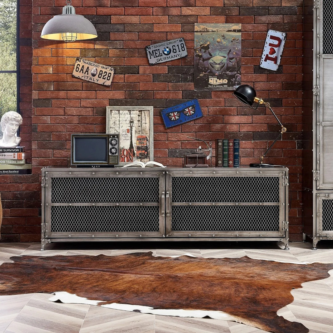 Industrial-style living room featuring a metal TV console with mesh doors, brick wall decor, vintage accents, and a rustic rug, linking to Loft Home's metal TV console collection.