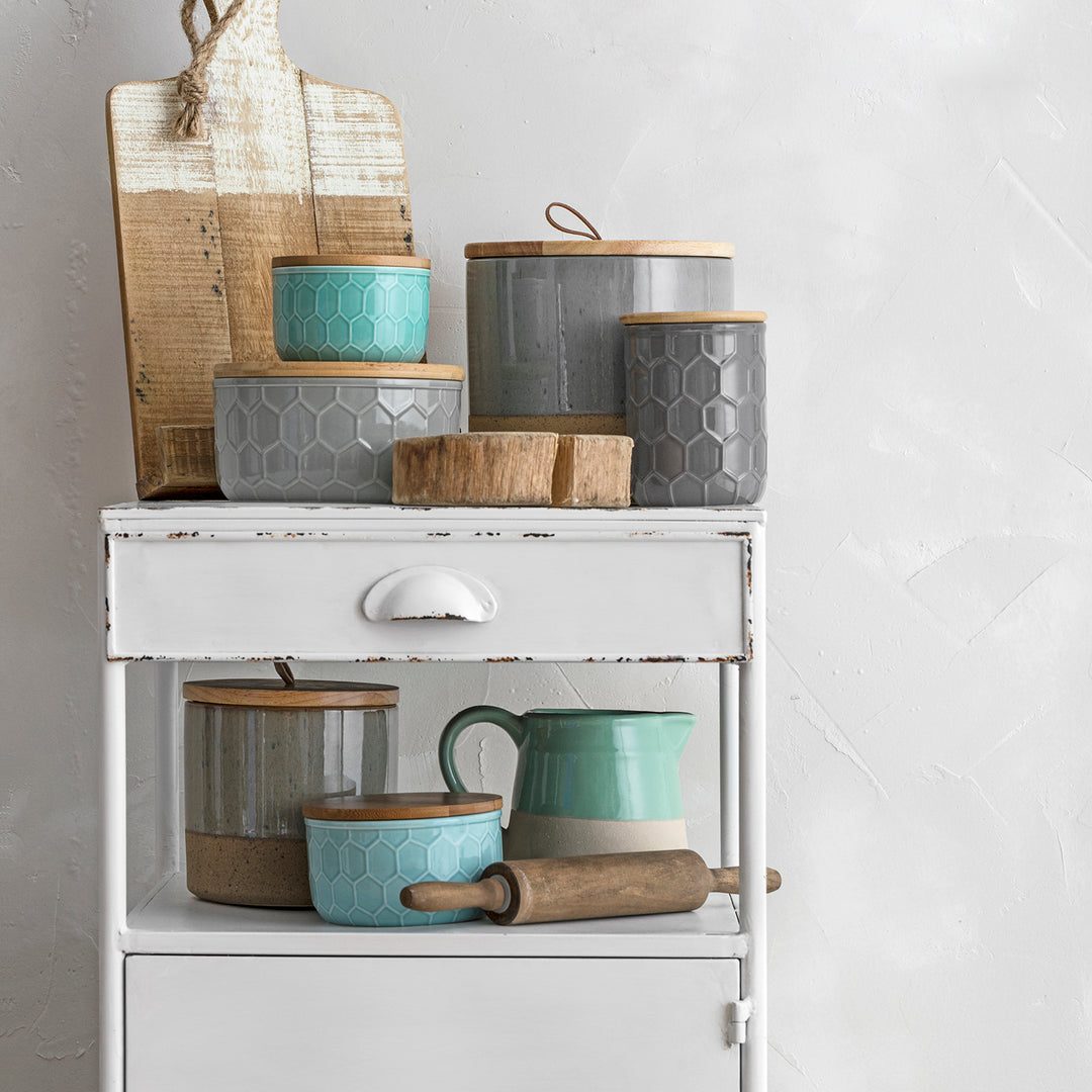 Rustic metal cabinet with a vintage-style drawer and an assortment of ceramic storage jars, adding farmhouse charm to any kitchen or living space.