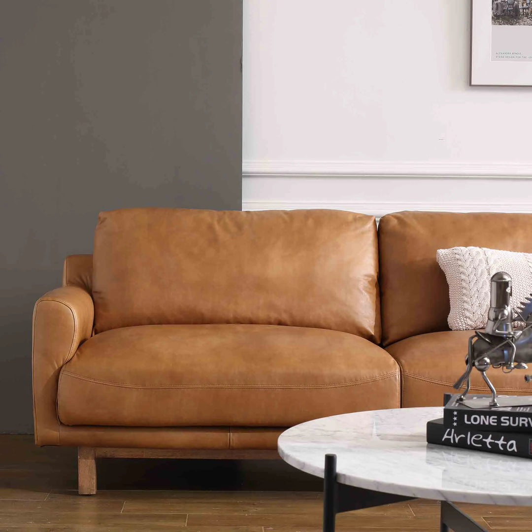 Featured in Loft Home's genuine leather sofas collection: Modern living room with a luxurious brown leather sofa, complemented by a stylish marble coffee table and cozy decor.