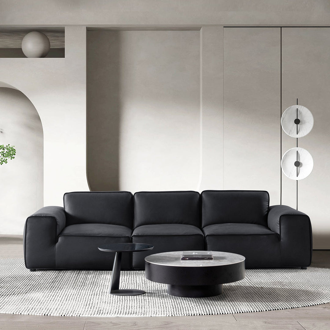 Modern living room featuring a sleek black microfiber leather sofa, paired with minimalist decor and a round coffee table for a sophisticated ambiance.