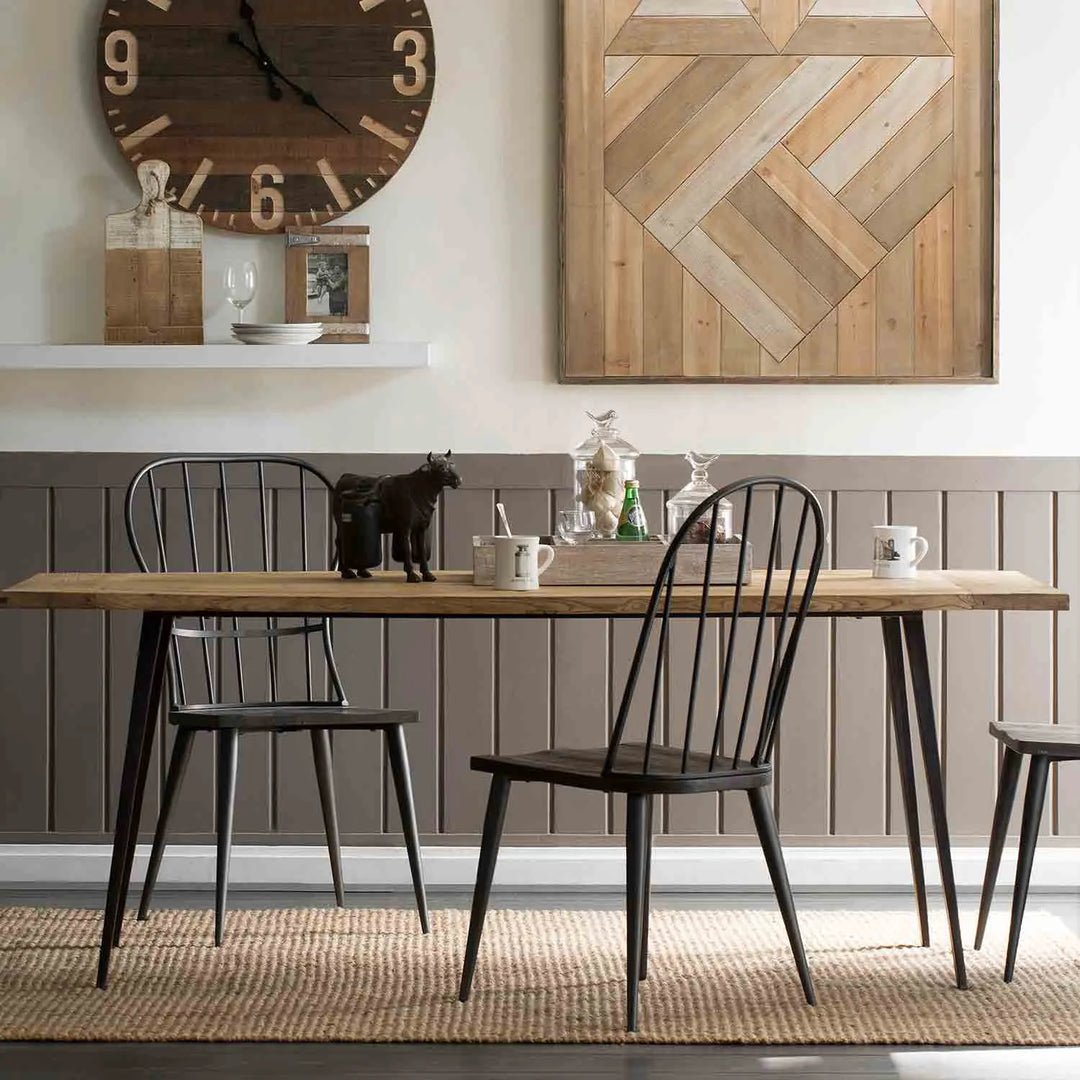 Featured in Loft Home's 8-12 seater tables collection: Rustic dining room with a large wooden table, black metal chairs, and vintage decor including a wooden clock and wall art.