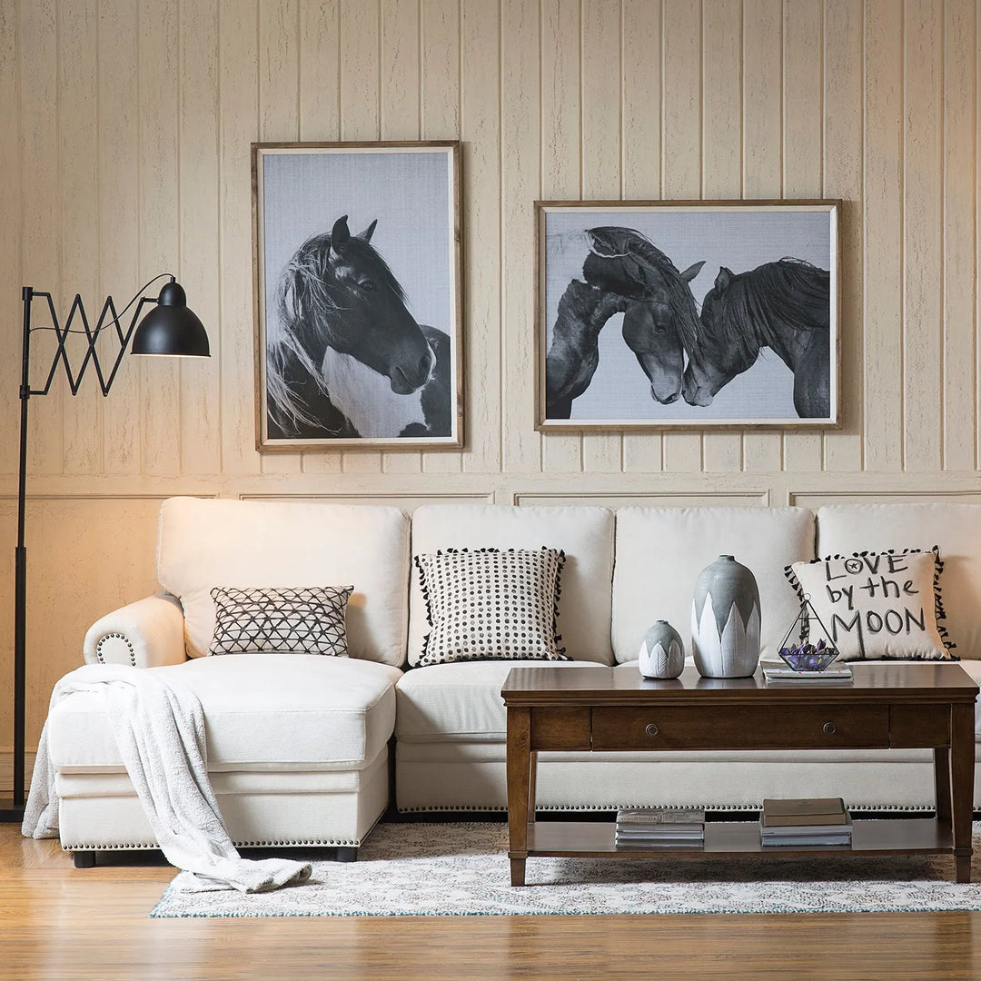 Modern living room featuring a stylish beige sectional sofa with decorative pillows, a wooden coffee table, and contemporary black and white horse artwork on the wall.