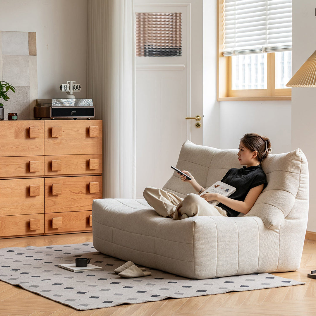Cozy modern living space with lounge chair, wooden storage drawers and soft textures, showcasing versatile furniture ideas for Singapore homes.