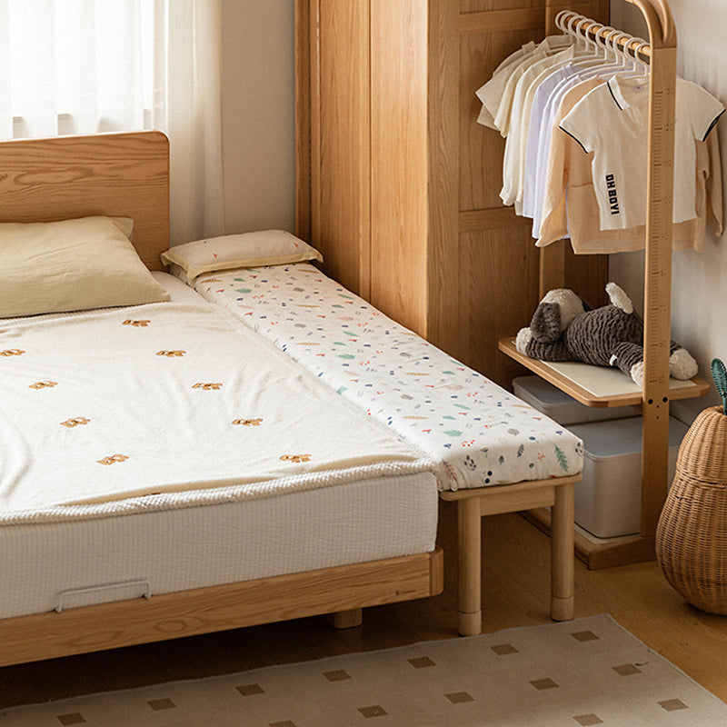 Cozy bedroom setup with a wooden bed frame, side mattress, and kid’s clothing rack, ideal for family-friendly and compact spaces.