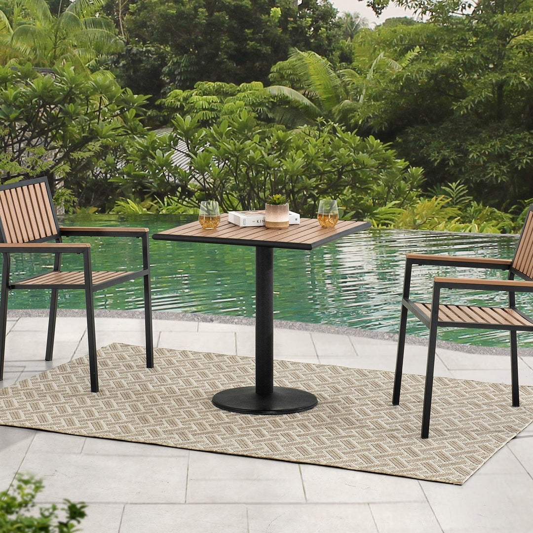 Loft Home outdoor dining table collection, featuring a sleek wood and metal square dining table with matching chairs, set by a serene poolside amidst lush greenery for relaxing outdoor meals.