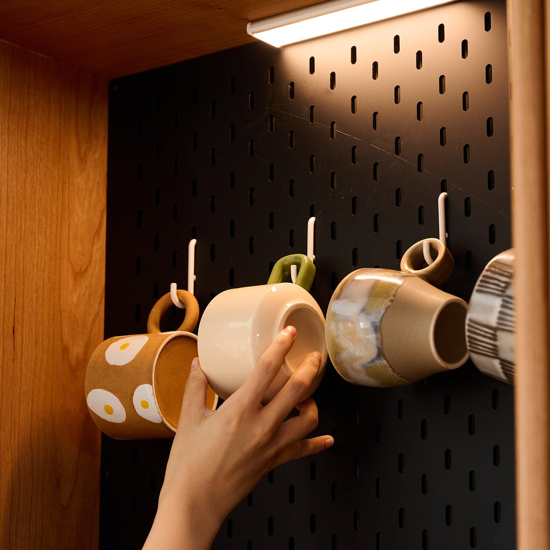 Loft Home Pegboard Storage collection, customizable black pegboard with hooks holding colorful mugs, ideal for efficient organization.