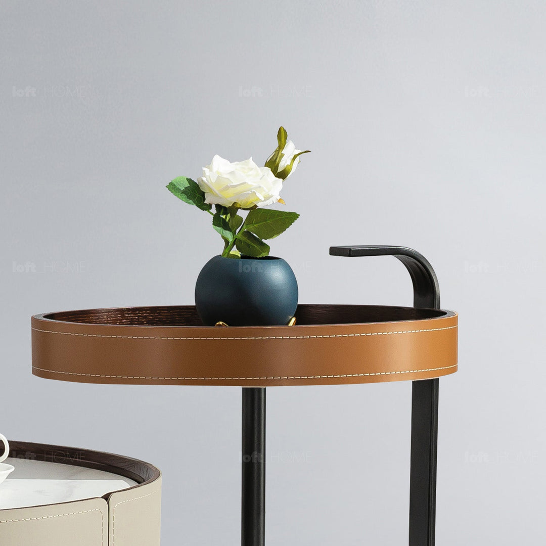 Loft Home PU Leather Tables Collection - Elegant round table with a sleek brown PU leather finish and black metal legs, showcasing a minimalistic vase decor for a modern home aesthetic